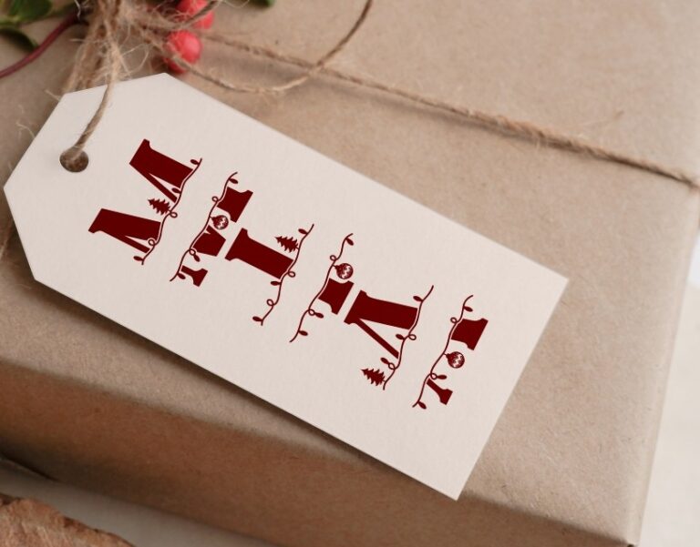 Christmas gift wrapped in brown paper with a white tag featuring a red festive monogram.
